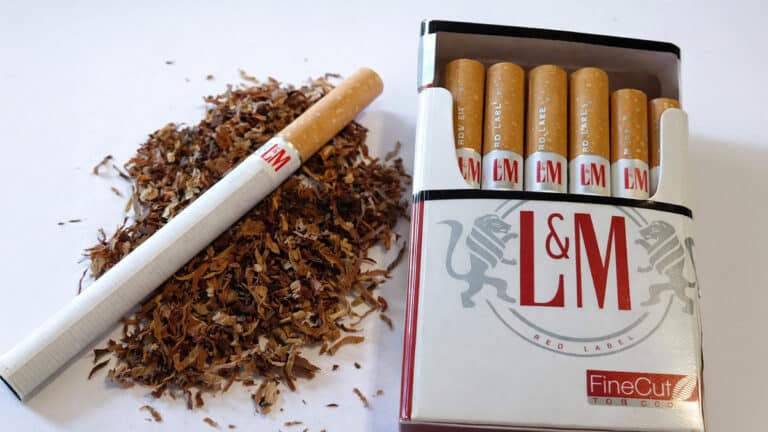 Close-up of L&M Red Label cigarettes with an open pack and loose tobacco, illustrating the cigarette products sold by Brooke Group in the late 1990s