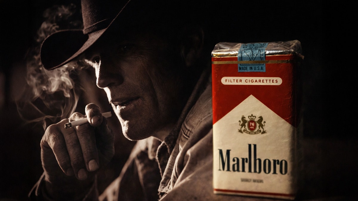 Dramatic low-light image of a cowboy smoking a cigarette beside a Marlboro pack, reflecting tobacco marketing and investor exposure in the early 2000s