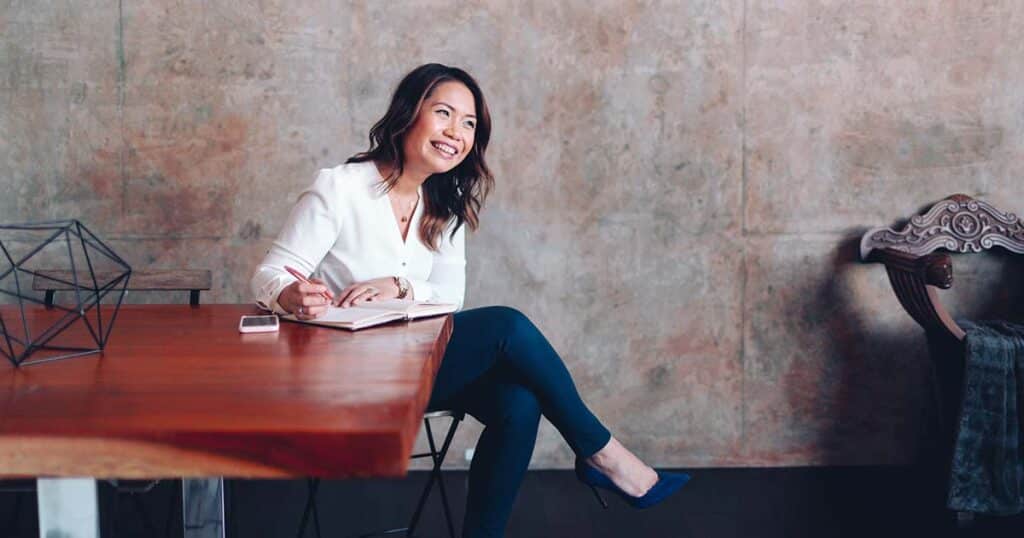 Asian woman smiling at table while taking notes